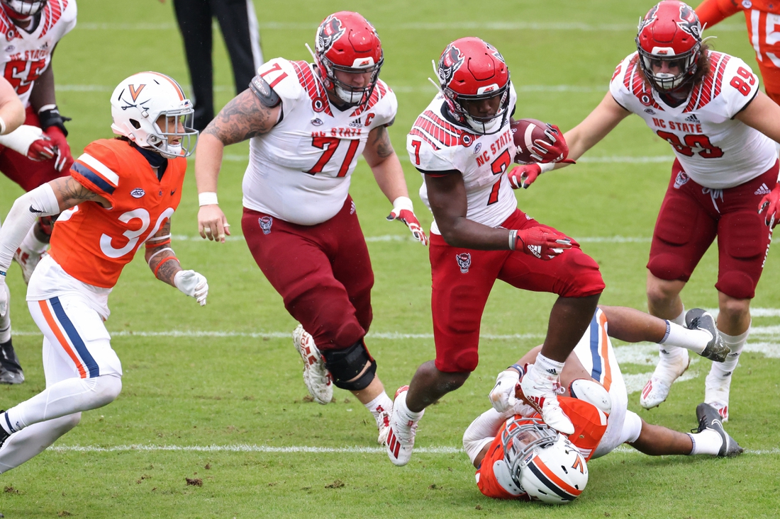 Oct 10, 2020; Charlottesville, Virginia, USA; North Carolina State Wolfpack running back Zonovan Knight (7) leaps over Virginia Cavaliers linebacker Charles Snowden (11) while carrying the ball in the fourth quarter at Scott Stadium. Mandatory Credit: Geoff Burke-USA TODAY Sports