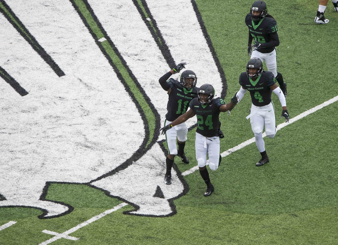 Oct 13, 2018; Denton, TX, USA; North Texas Mean Green defensive back Cam Johnson (11) and defensive back Taylor Robinson (24) and safety Khairi Muhammad (4) and defensive back Jameel Moore (39) celebrate a stop of the Southern Miss Golden Eagles during the first half at Apogee Stadium. Mandatory Credit: Jerome Miron-USA TODAY Sports