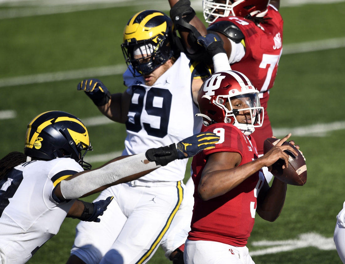 Nov 7, 2020; Bloomington, Indiana, USA; Indiana Hoosiers quarterback Michael Penix Jr. (9) narrowly escapes being sacked by Michigan Wolverines defensive lineman Luiji Vilain (18) during the second half of the game at Memorial Stadium. The Indiana Hoosiers defeated the Michigan Wolverines 38 to 21. Mandatory Credit: Marc Lebryk-USA TODAY Sports