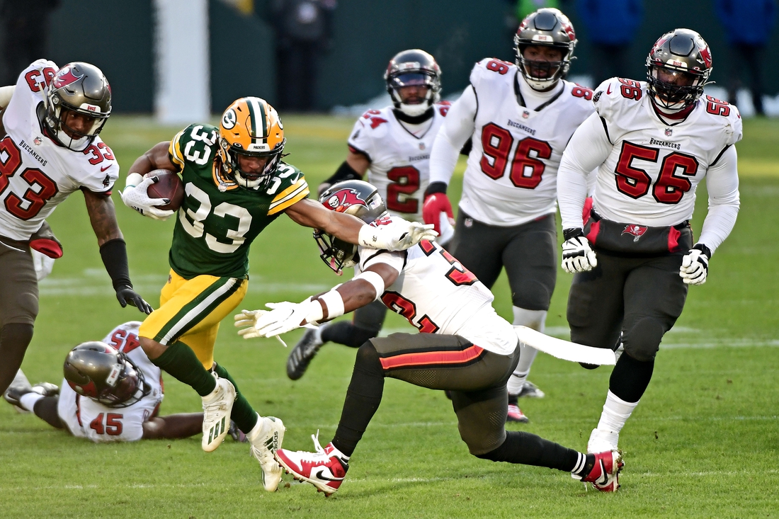 Jan 24, 2021; Green Bay, Wisconsin, USA; Green Bay Packers running back Aaron Jones (33) runs the ball against Tampa Bay Buccaneers safety Mike Edwards (32) in the NFC Championship Game at Lambeau Field . Mandatory Credit: Benny Sieu-USA TODAY Sports