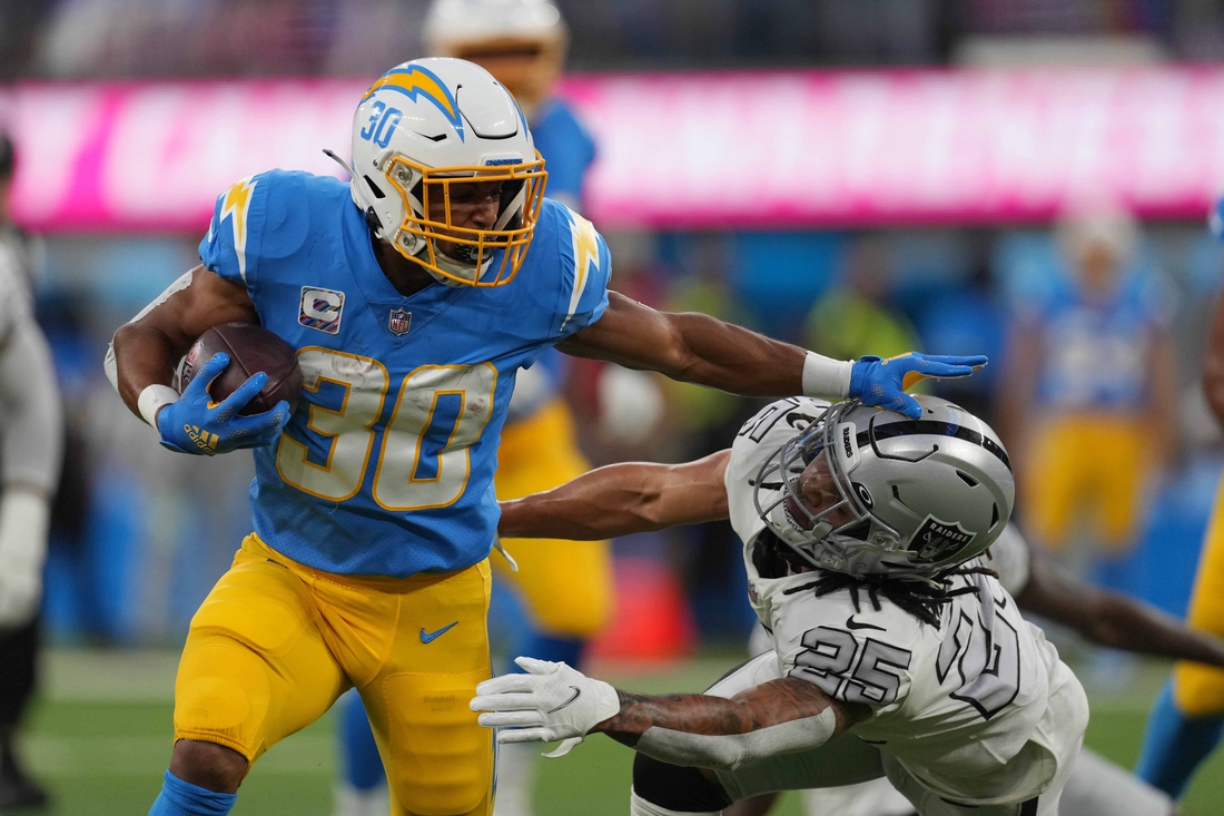 Oct 4, 2021; Inglewood, California, USA; Los Angeles Chargers running back Austin Ekeler (30) stiff arms Las Vegas Raiders defensive back Johnathan Abram (24) in the first half at SoFi Stadium. The Chargers defeated the Raiders 28-14. Mandatory Credit: Kirby Lee-USA TODAY Sports