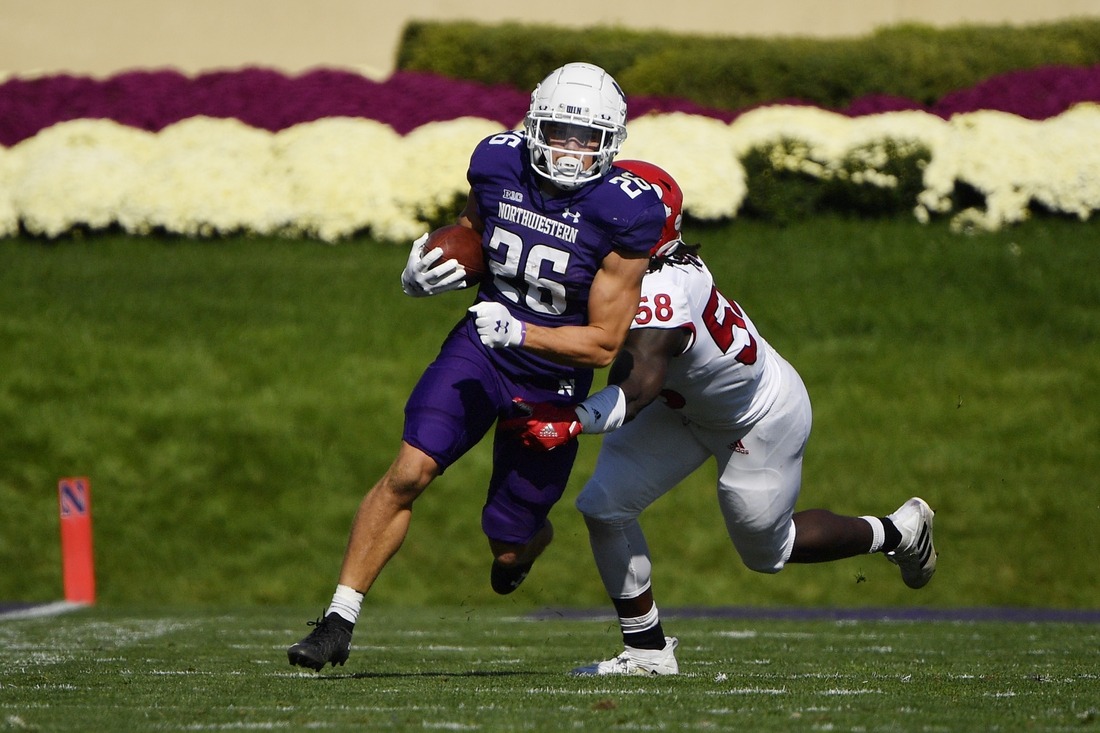 Oct 16, 2021; Evanston, Illinois, USA; Northwestern Wildcats running back Evan Hull (26) runs with the football in the first half against Rutgers Scarlet Knights linebacker Mohamed Toure (58) at Ryan Field. Mandatory Credit: Quinn Harris-USA TODAY Sports