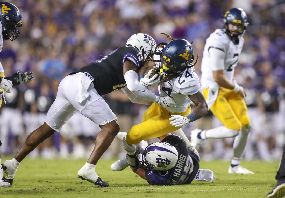 Oct 23, 2021; Fort Worth, Texas, USA; West Virginia Mountaineers running back Tony Mathis Jr. (24) runs the ball and is tackled by TCU Horned Frogs linebacker Dee Winters (13) and TCU Horned Frogs linebacker Wyatt Harris (25) during the first quarter at Amon G. Carter Stadium. Mandatory Credit: Ben Queen-USA TODAY Sports