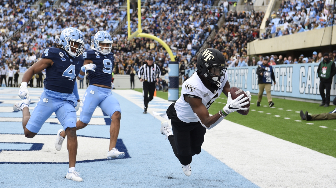 Nov 6, 2021; Chapel Hill, North Carolina, USA; Wake Forest Demon Deacons wide receiver Jaquarii Roberson (5) catches a touchdown pass as North Carolina Tar Heels defensive backs Trey Morrison (4) and Cam'Ron Kelly (9) defend in the second quarter at Kenan Memorial Stadium. Mandatory Credit: Bob Donnan-USA TODAY Sports