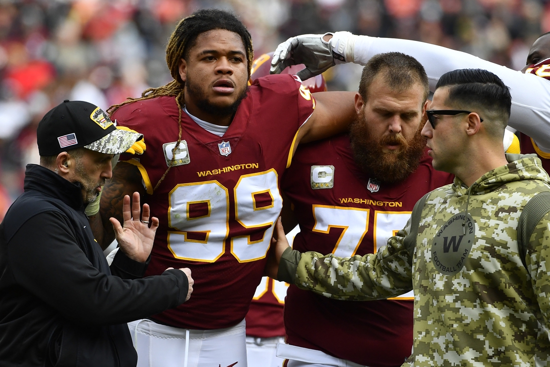 Nov 14, 2021; Landover, Maryland, USA; Washington Football Team defensive end Chase Young (99) is helped off the field by guard Brandon Scherff (75) after suffering an apparent injury against the Tampa Bay Buccaneers during the first half at FedExField. Mandatory Credit: Brad Mills-USA TODAY Sports