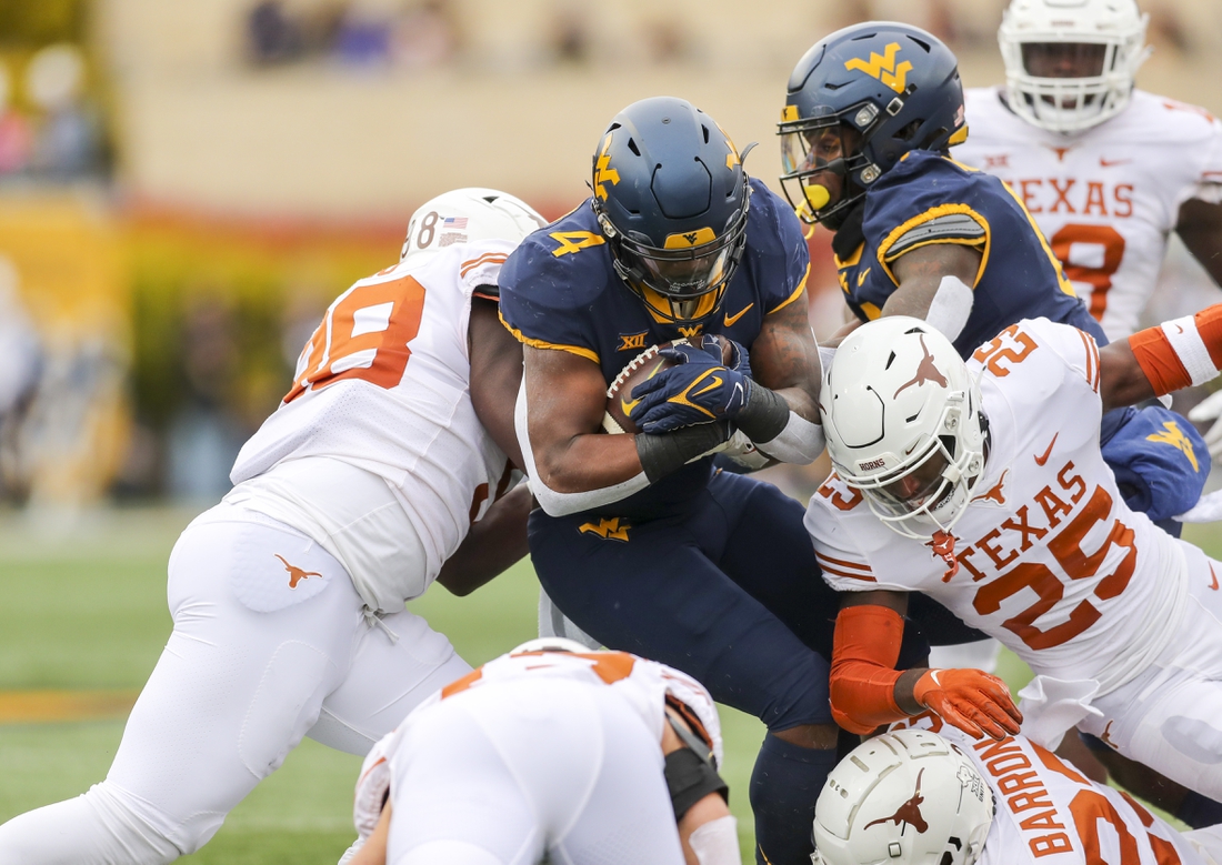 Nov 20, 2021; Morgantown, West Virginia, USA; West Virginia Mountaineers running back Leddie Brown (4) runs the ball and is tackled by many Texas Longhorns defenders during the first quarter at Mountaineer Field at Milan Puskar Stadium. Mandatory Credit: Ben Queen-USA TODAY Sports