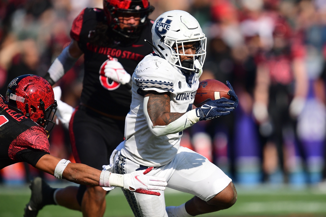 Dec 4, 2021; Carson, CA, USA; Utah State Aggies running back Calvin Tyler Jr. (4) runs the ball against San Diego State Aztecs safety C.J. Baskerville (34) during the first half of the Mountain West Conference championship game at Dignity Health Sports Park. Mandatory Credit: Gary A. Vasquez-USA TODAY Sports