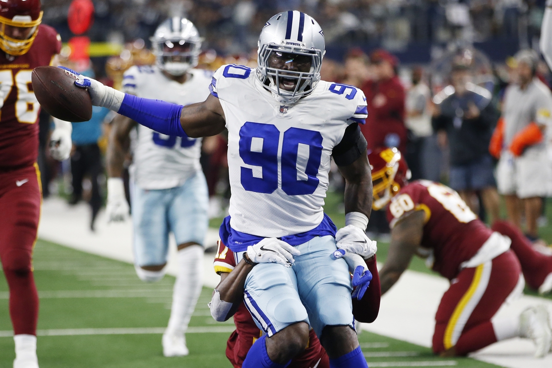 Dec 26, 2021; Arlington, Texas, USA; Dallas Cowboys defensive end Demarcus Lawrence (90) returns an interception for a touchdown in the first quarter against the Washington Football Team at AT&T Stadium. Mandatory Credit: Tim Heitman-USA TODAY Sports
