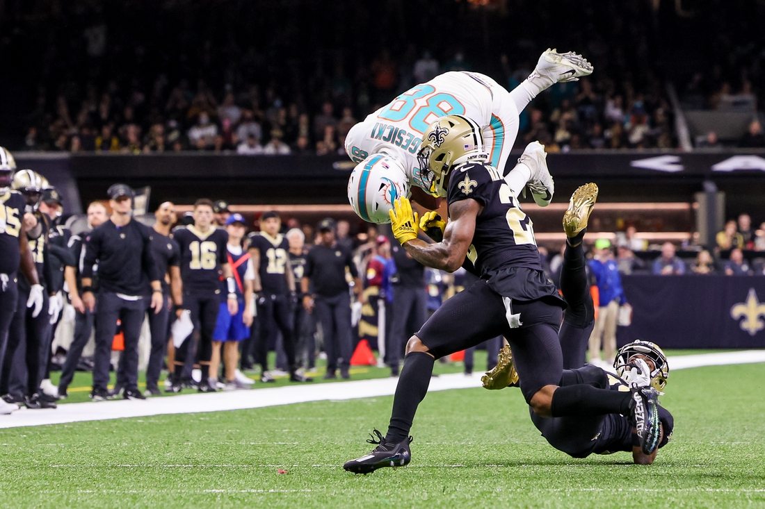 Dec 27, 2021; New Orleans, Louisiana, USA; Miami Dolphins tight end Mike Gesicki (88) leaps over New Orleans Saints cornerback Paulson Adebo (right) during the first half at Caesars Superdome. Mandatory Credit: Stephen Lew-USA TODAY Sports