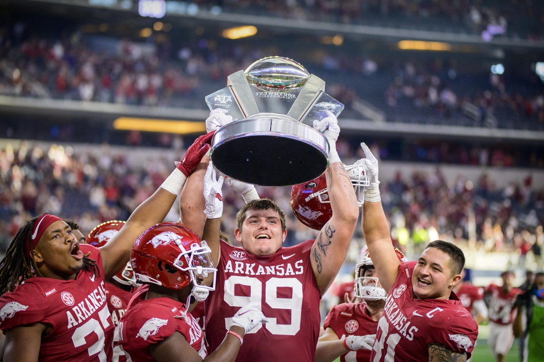 Sep 25, 2021; Arlington, Texas, USA;  Arkansas Razorbacks defensive lineman Eric Thomas Jr. (37) and defensive lineman John Ridgeway (99) and linebacker Grant Morgan (31) hold up the Southwest Classic trophy as they celebrate the win over the Texas A&M Aggies at AT&T Stadium. Mandatory Credit: Jerome Miron-USA TODAY Sports
