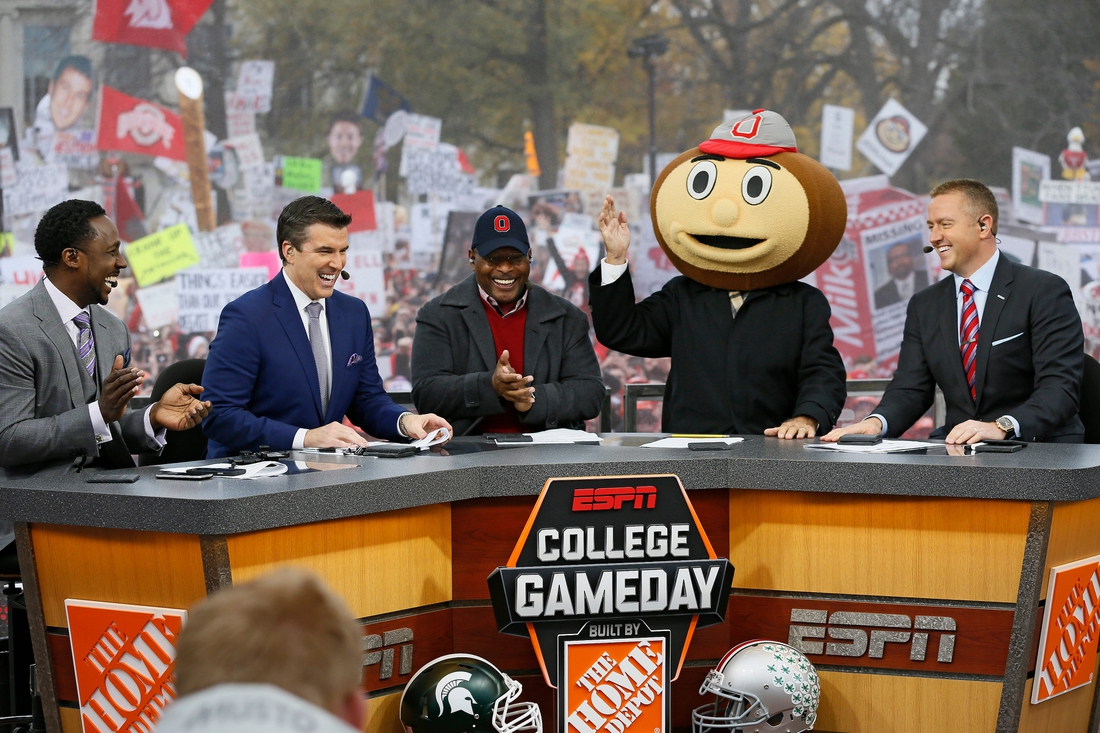 Lee Corso waves while wearing a Brutus Buckeye head as, from left, Desmond Howard, Rece Davis, Archie Griffin, and Kirk Herbstreit applaud his pick during ESPN's College GameDay broadcast from the campus of Ohio State prior to the NCAA football game against the Michigan State Spartans in Columbus on Nov. 21, 2015. (Adam Cairns / The Columbus Dispatch)Osu15msu Ac 07