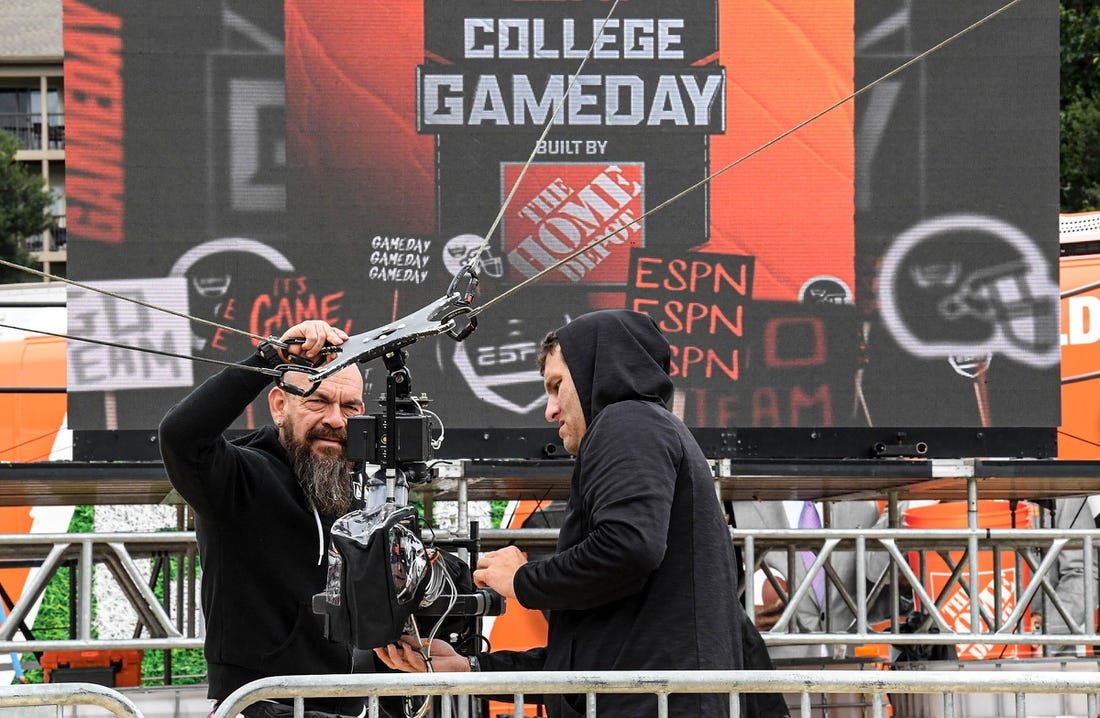 ESPN staff cover a video camera to protect from Hurricane Ian rain, on the ESPN College GameDay Built by The Home Depot set on Bowman Field at Clemson University in Clemson Friday, September 30, 2022. The show's 427th road show, the eighth at Clemson before the game with NC State, airs on television from 9 a.m. to noon Eastern time.

Espn College Gameday On Bowman Field At Clemson