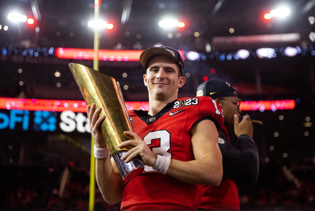 Jan 9, 2023; Inglewood, CA, USA; Georgia Bulldogs quarterback Stetson Bennett (13) celebrates with the championship trophy after defeating the TCU Horned Frogs during the CFP national championship game at SoFi Stadium. Mandatory Credit: Mark J. Rebilas-USA TODAY Sports