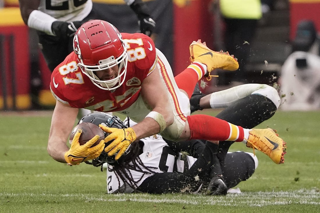 Jan 21, 2023; Kansas City, Missouri, USA; Kansas City Chiefs tight end Travis Kelce (87) moves the ball ahead of Jacksonville Jaguars safety Rayshawn Jenkins (2) during the first half in the AFC divisional round game at GEHA Field at Arrowhead Stadium. Mandatory Credit: Denny Medley-USA TODAY Sports