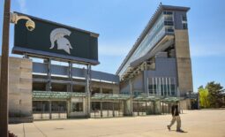 A passerby walks past a camera mounted outside the north entrance of Spartan Stadium, Wednesday, May 10, 2023.