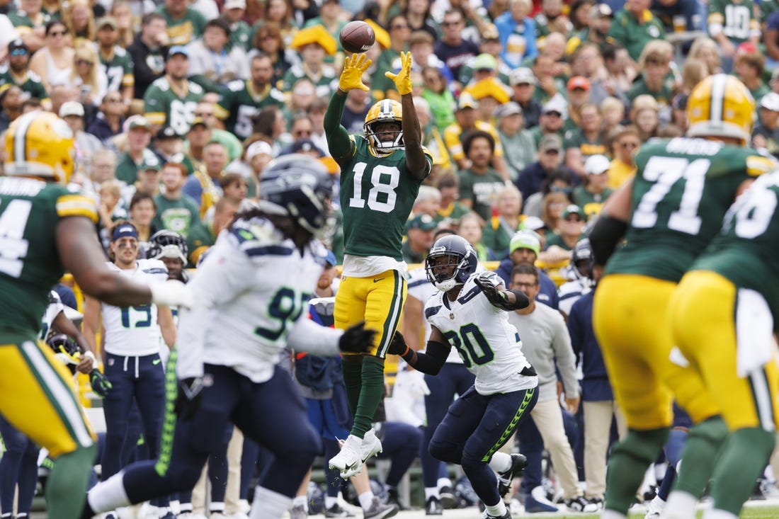Aug 26, 2023; Green Bay, Wisconsin, USA;  Green Bay Packers wide receiver Malik Heath (18) leaps to catch a pass in front of Seattle Seahawks cornerback Michael Jackson (30) during the first quarter at Lambeau Field. Mandatory Credit: Jeff Hanisch-USA TODAY Sports