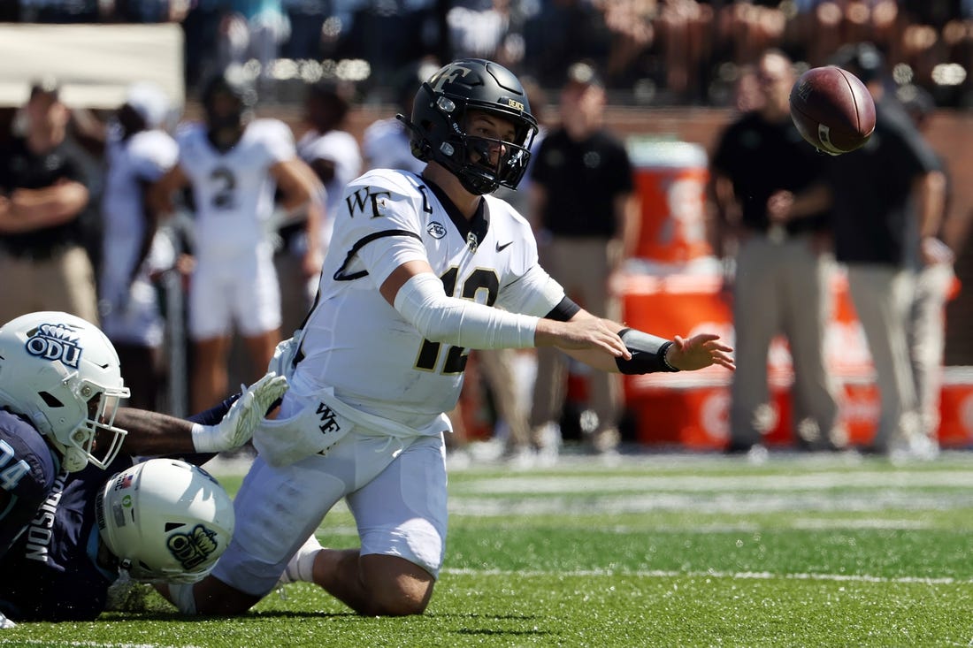 Sep 16, 2023; Norfolk, Virginia, USA; Wake Forest Demon Deacons quarterback Mitch Griffis (12) fumbles the ball while being tackled by Old Dominion Monarchs defensive end Amorie Morrison (4) and linebacker EJ Green (24) during the second quarter at Kornblau Field at S.B. Ballard Stadium. Mandatory Credit: Peter Casey-USA TODAY Sports