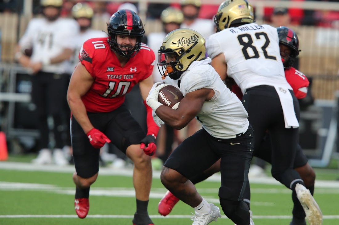Nov 18, 2023; Lubbock, Texas, USA;  Central Florida Knights running back RJ Harvey (7) rushes against Texas Tech Red Raiders defensive end Jacob Rodriguez (10) in the first half at Jones AT&T Stadium and Cody Campbell Field. Mandatory Credit: Michael C. Johnson-USA TODAY Sports