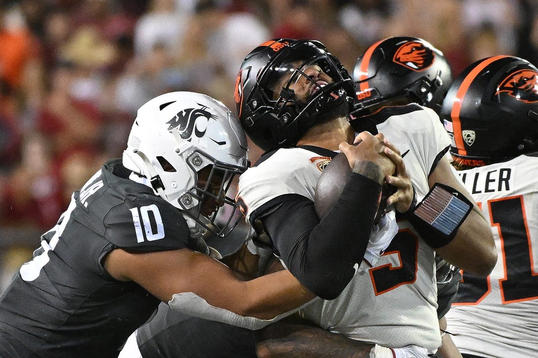 Sep 23, 2023; Pullman, Washington, USA; Oregon State Beavers quarterback DJ Uiagalelei (5) is stopped by Washington State Cougars defensive end Ron Stone Jr. (10) in the second half at Gesa Field at Martin Stadium. Mandatory Credit: James Snook-USA TODAY Sports
